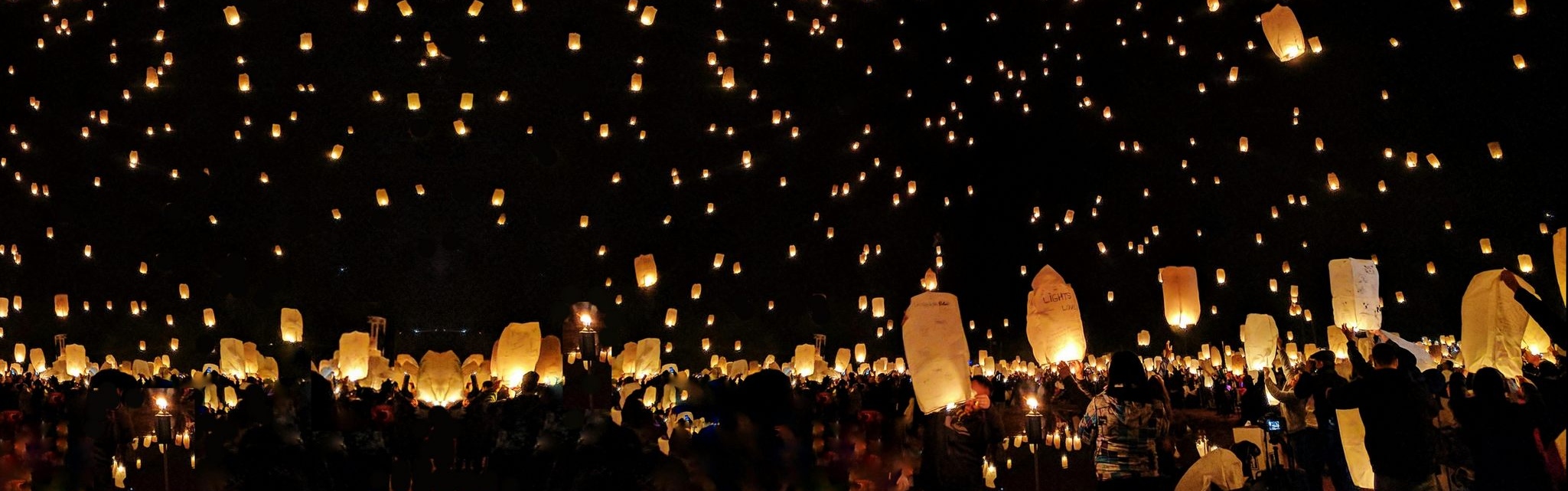 Des milliers de lanternes de papier s'envolent dans le ciel de la nuit.